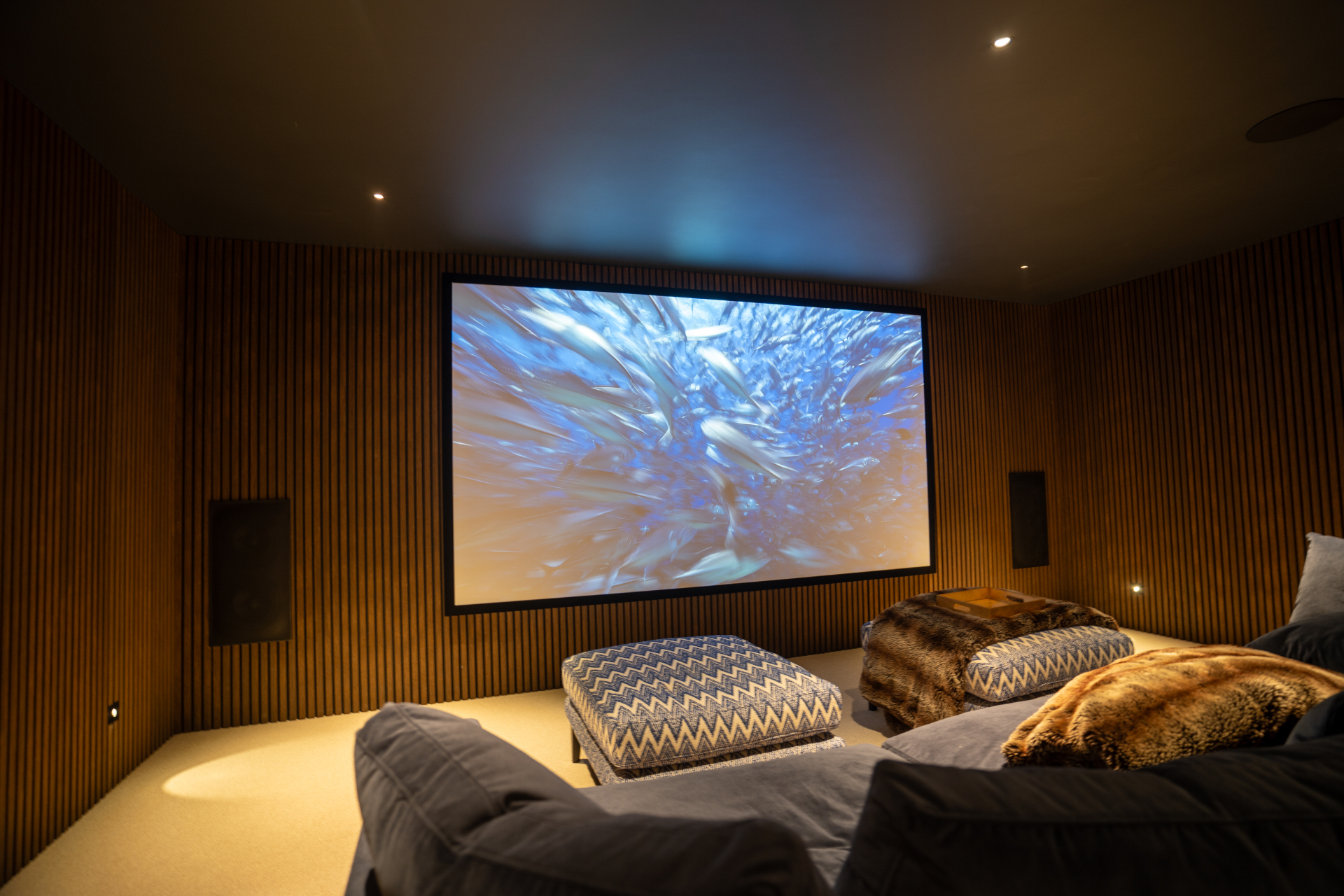 The completed private cinema in Surrey with projection screen and slatted timber walls